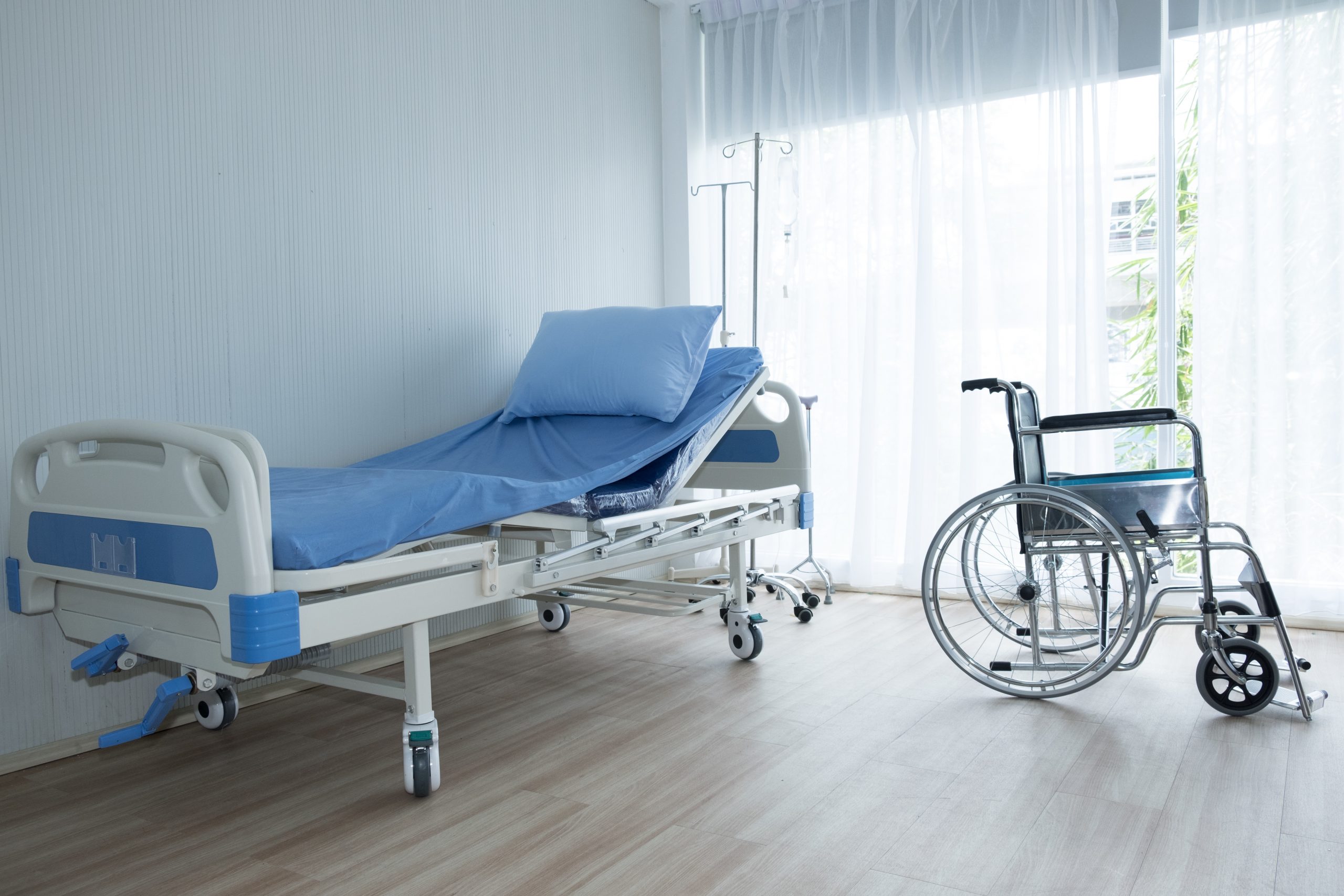 Wheelchair and patient bed in the room of hospital
